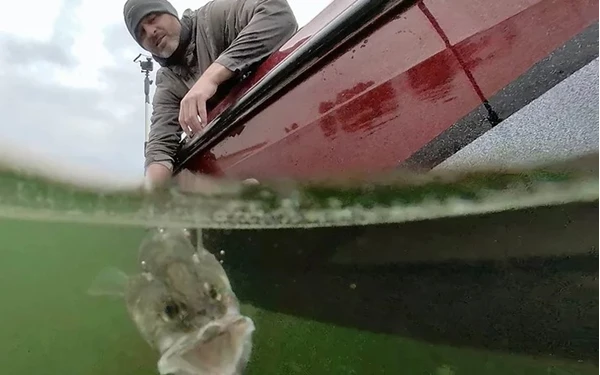 Man pulling fish from water.